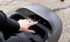 Woman adjusts air intensity settings on a modern grey electronic foot massager.