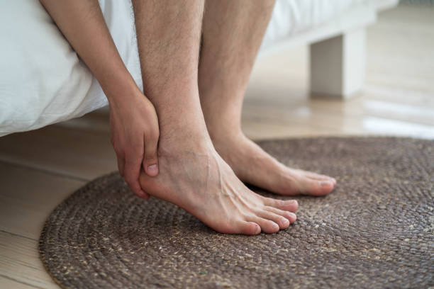Relieve aching feet with a foot massager; man holds his sore ankle.